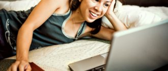 девушка, улыбаясь, смотрит в ноутбук